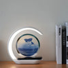 Modern LED desk lamp with circular blue sand art and phone holder on wooden table near books