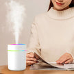 Woman reading magazine next to white LED aroma diffuser with visible mist on table