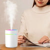 Woman reading magazine next to white LED aroma diffuser with visible mist on table