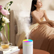 Modern bedroom scene with woman, colorful LED humidifier, flowers, and tea on nightstand