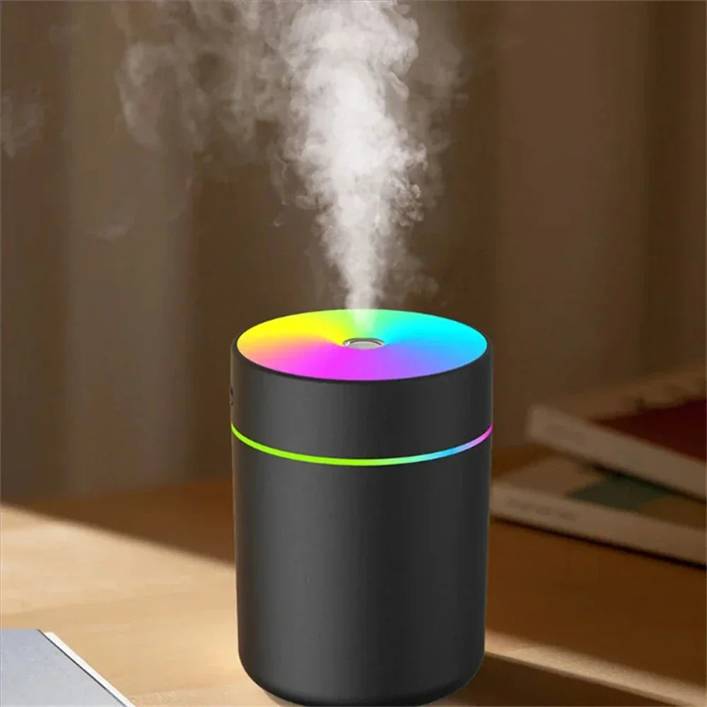 Black aroma diffuser with colorful LED light and visible mist on a wooden table indoors
