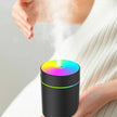 Hand over a black portable humidifier with rainbow LED lights releasing mist indoors