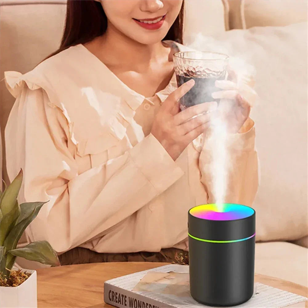 Woman relaxing with a glass of drink near a colorful LED humidifier on a coffee table