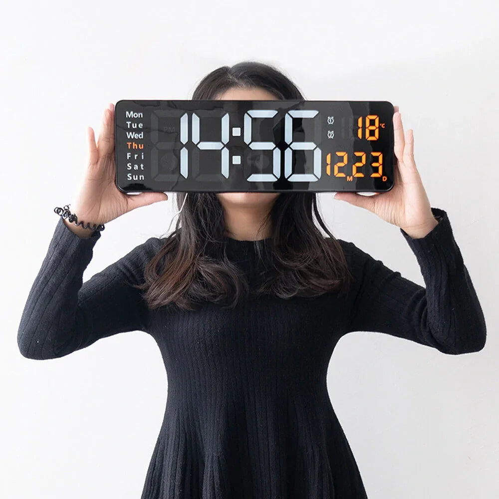 Woman in black dress holding large digital wall clock with calendar and temperature display
