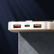 Close-up of a beige power bank with two USB-A and one USB-C ports on dark background.