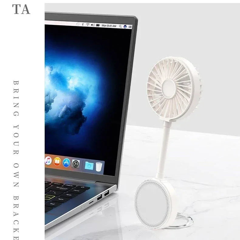 Compact white portable desk fan beside laptop on white marble surface
