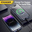 ESSAGER power bank charging two smartphones at once, wireless and wired, on a dark desk