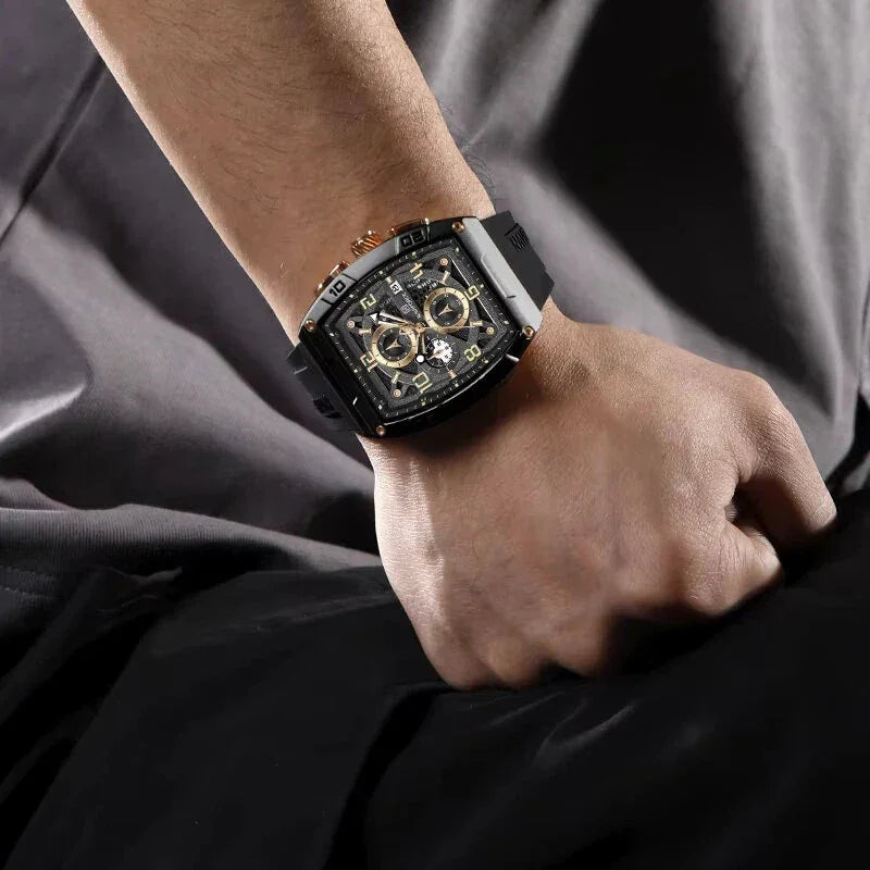 Man wearing a black square chronograph watch with gold accents on wrist
