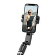Smartphone on selfie stick with camera app and woman in sunglasses on screen