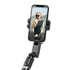 Smartphone on selfie stick with camera app and woman in sunglasses on screen