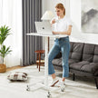 Woman using laptop at adjustable standing desk with wheels in modern living room