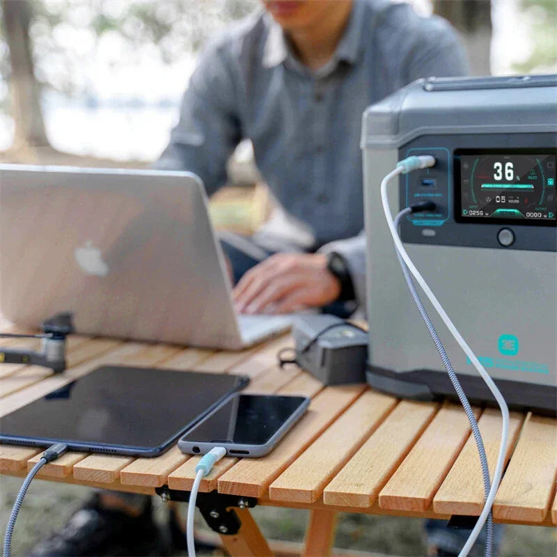 Portable power station charging laptop, tablet, and phone on outdoor wooden table
