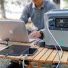 Portable power station charging laptop, tablet, and phone on outdoor wooden table