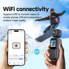 Hand holding action camera with WiFi connectivity and smartphone, snowboarder in background