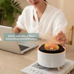 Desktop flame-effect humidifier emitting mist near woman working on laptop at home office
