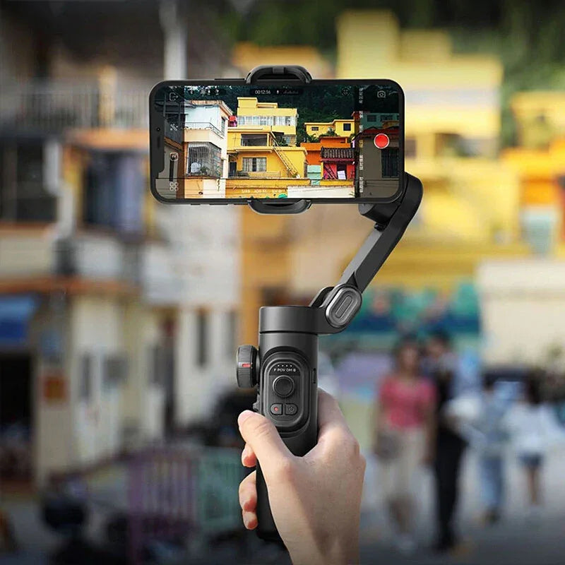 Hand holding smartphone gimbal stabilizer filming colorful buildings outdoors