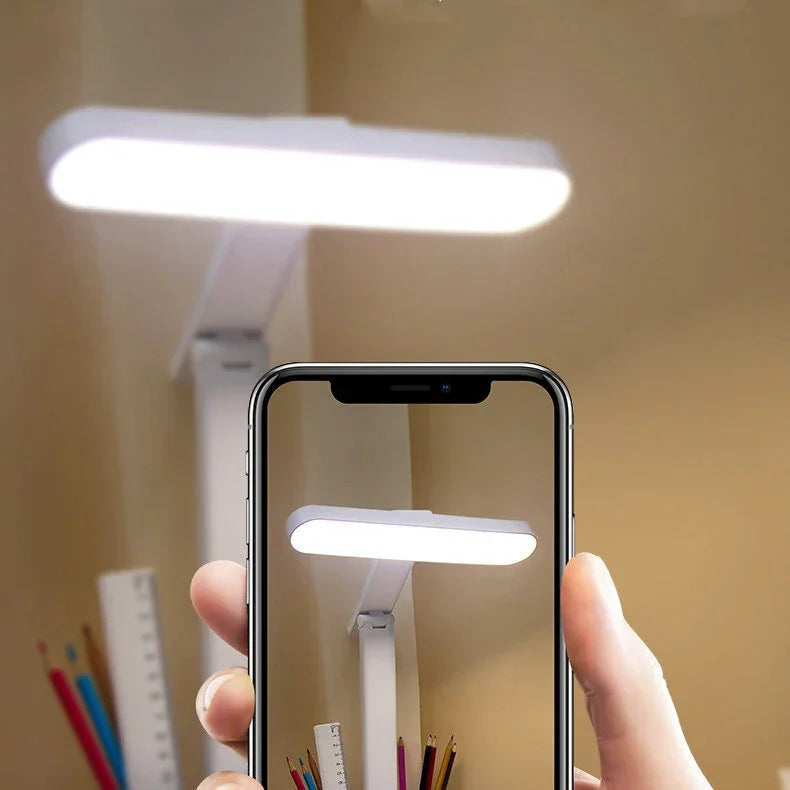 Person taking photo of modern white LED desk lamp above organized pencils and ruler