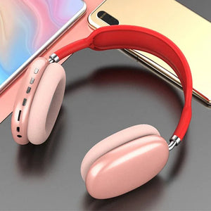 Pink wireless Bluetooth headset with red headband on a modern desk near smartphones